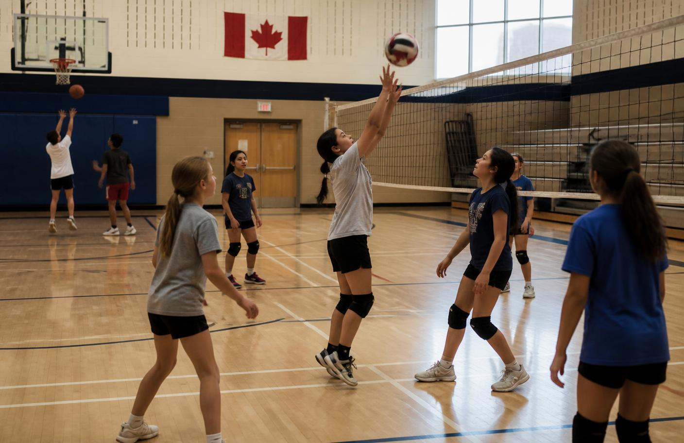 Teens playing volleyball and basketball together during practice in a school gymnasium